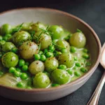 Creamed peas and pearl onions in a bowl with herbs and light seasoning.
