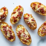 Crispy loaded baked potato skins topped with cheese and bacon arranged neatly on a white background.