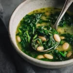 Spinach & White Bean Soup 3 close-up of spinach and white bean soup with spoon showing tender beans and wilted spinach