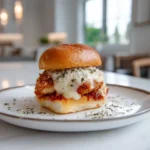 Chicken Parmesan Sliders 3 Single chicken parmesan slider on a white plate with crispy breaded chicken, marinara sauce, and melted mozzarella cheese.