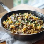 Beef Stroganoff Skillet 3 One-pan beef stroganoff skillet with egg noodles, tender beef pieces, and creamy mushroom sauce garnished with herbs.