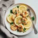 Shrimp Piccata 3 plated shrimp piccata with lemon slices and parsley on a white plate