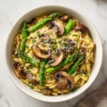 Creamy Mushroom Asparagus Orzo 3 Bowl of creamy orzo with mushrooms and asparagus topped with grated Parmesan and fresh herbs.