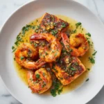 Plated Cajun salmon and shrimp with garlic butter sauce and fresh parsley on a white plate.