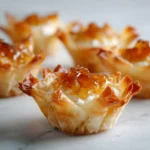 golden baked phyllo cups filled with whipped goat cheese and topped with honey, arranged on a light marble surface